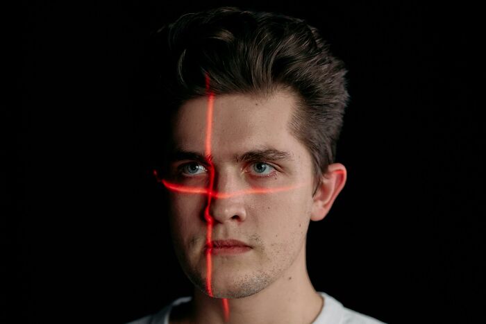 Young man with intense gaze and red laser lines crossing his face, illustrating the picking the wrong line concept.