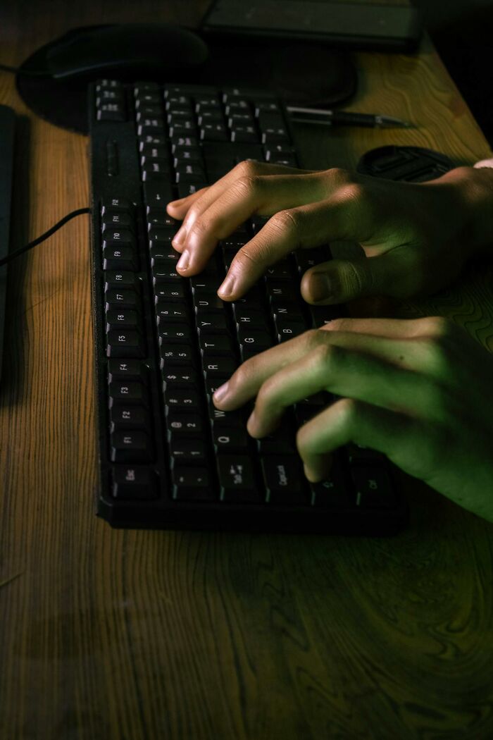 Hands typing on a keyboard during a night shift, illustrating night shift workers and chilling paranormal encounters theme.