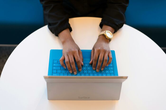 Person typing on a blue keyboard laptop, illustrating the concept of picking the wrong line at the grocery store frustration.