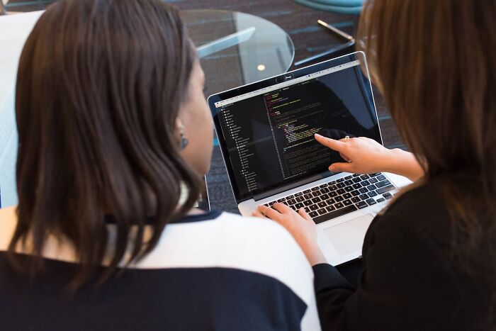Two women reviewing code on a laptop during a job interview, highlighting potential red flags of toxic workplace culture.