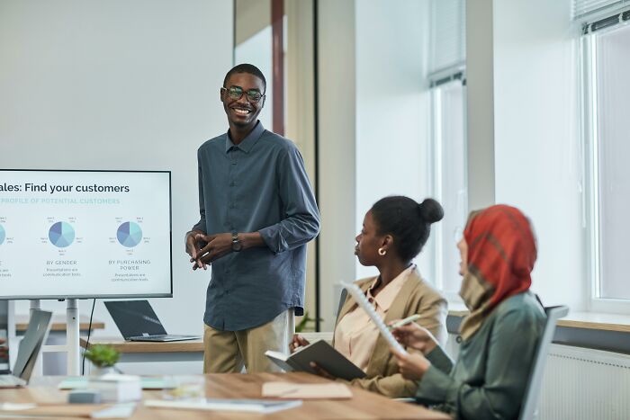 Man presenting sales data on screen to colleagues in a modern office, illustrating picking the wrong line at the grocery store.