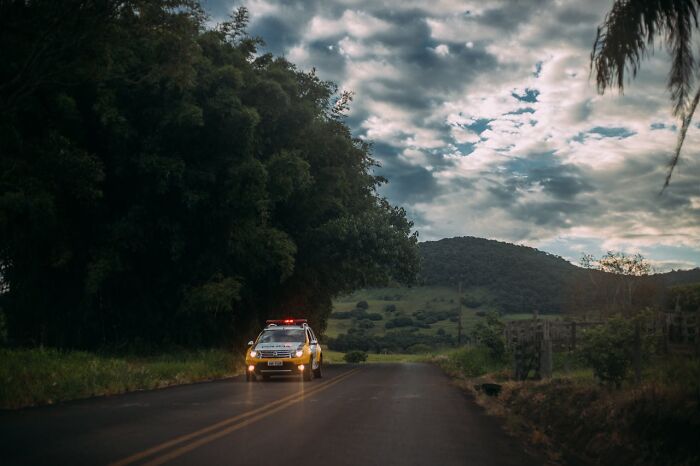 Police car on a dark rural road at night, depicting night shift workers and chilling paranormal encounters in an eerie setting.