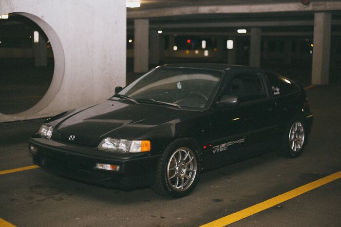 Black vintage car parked in a dimly lit garage, symbolizing stories of people surviving crazy situations.