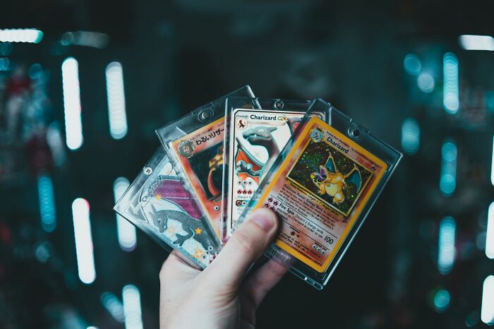 Hand holding a fan of rare collectible Charizard Pokemon cards representing heartwarming secrets collection.