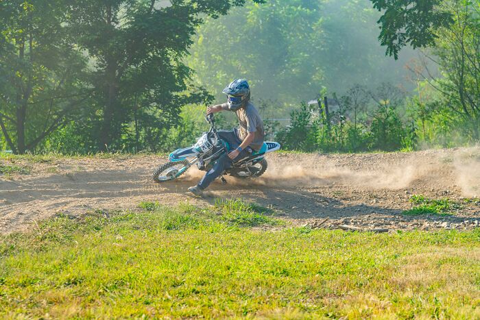 Person riding a dirt bike kicking up dust outdoors, illustrating adventurous ways to avoid babysitting duties.