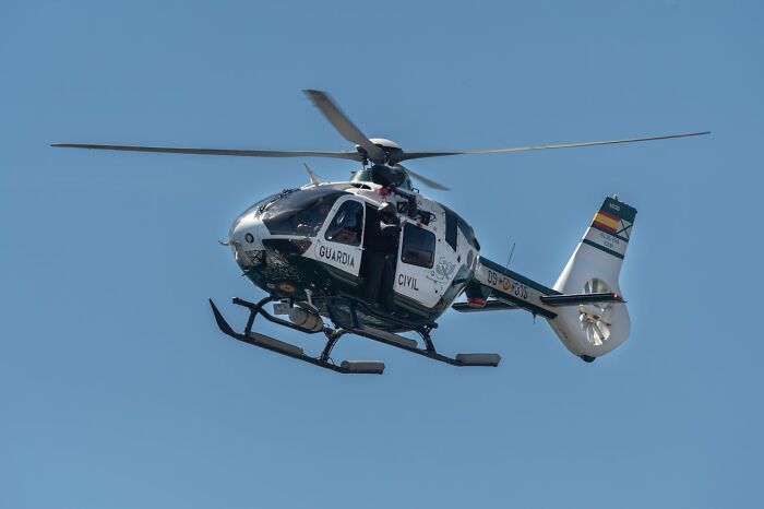 Police helicopter flying in clear blue sky during a rescue mission showing people surviving crazy situations.