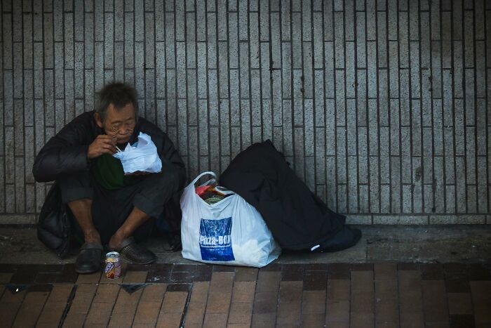 Man sitting on sidewalk eating food with bags beside him, highlighting safe things that people worry about online.
