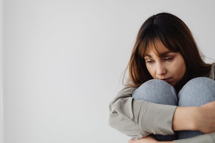 Young woman sitting alone, looking thoughtful and pensive, representing people surviving crazy situations.