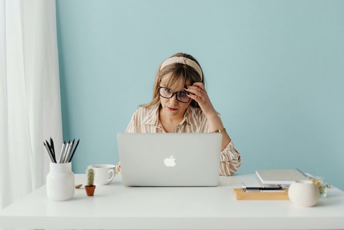 Woman wearing glasses concentrating on a cognitive ability test on her laptop in a calm, minimalistic workspace.