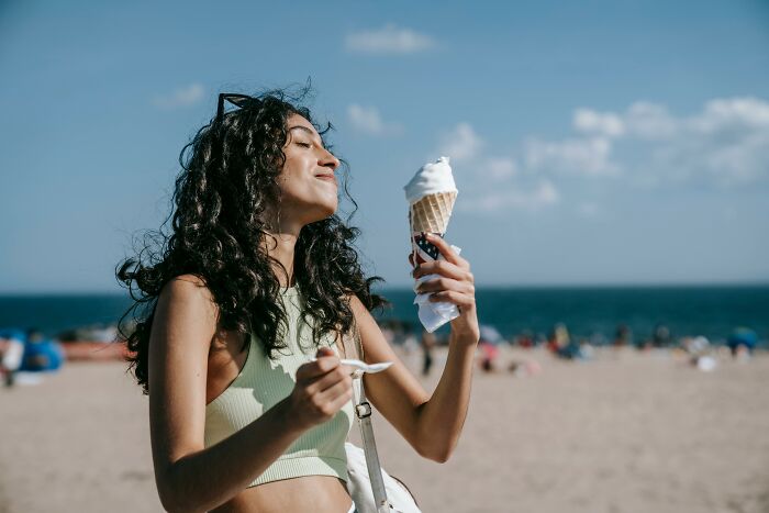 Young woman enjoying ice cream cone on the beach, one of the totally safe things people can’t stop freaking out about