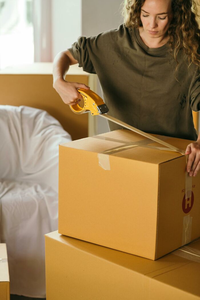 Woman packing boxes with tape in a room, illustrating people who actually experienced psychic predictions.