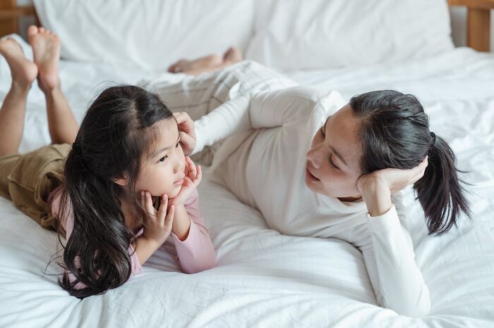 Mother and daughter lying on bed, sharing a quiet moment while discussing kids' imaginary friends and creepy experiences.