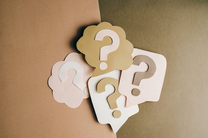 Paper cutouts of question marks in speech bubbles on a brown background representing general knowledge quiz challenges. Paper cutouts of question marks in speech bubbles on a brown background representing general knowledge quiz challenges.