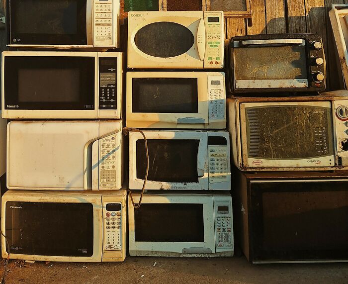 Stack of old microwaves in various conditions, illustrating totally safe things that people find surprisingly alarming.
