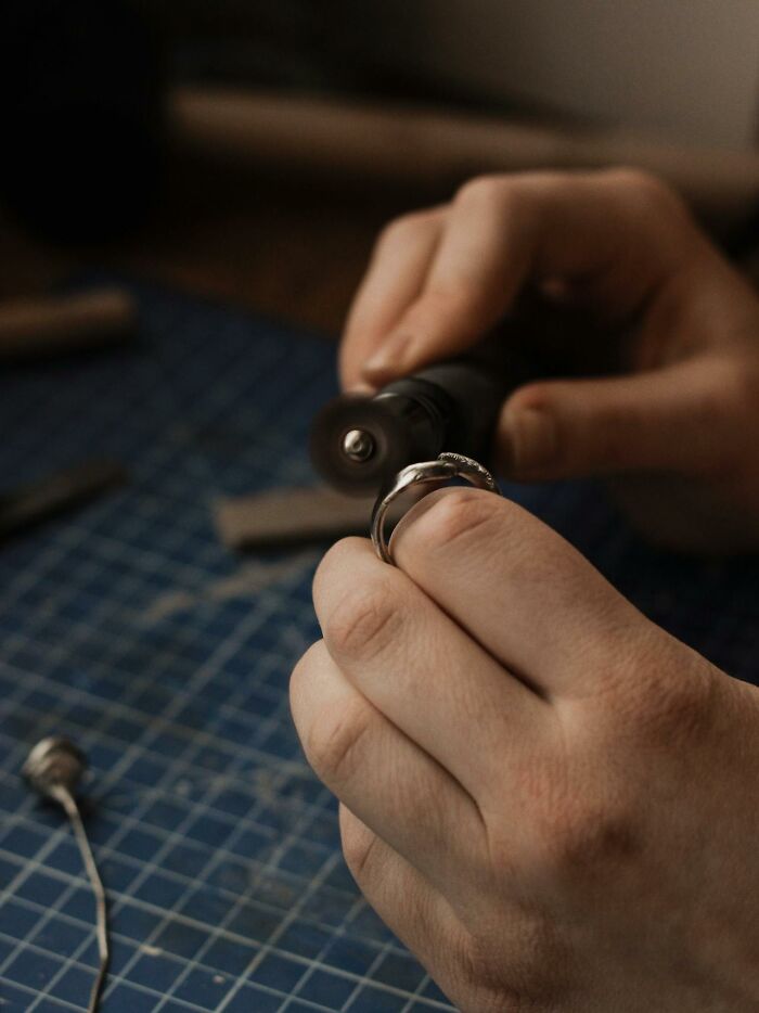 Close-up of hands polishing a silver ring, capturing a heartwarming and harmless secret moment of craftsmanship.