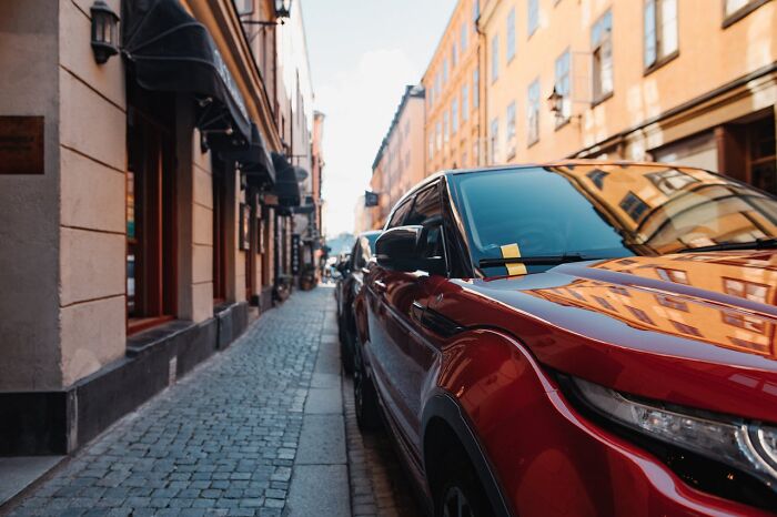 Red car parked on a narrow cobblestone street lined with buildings, highlighting PR campaign decisions that failed.