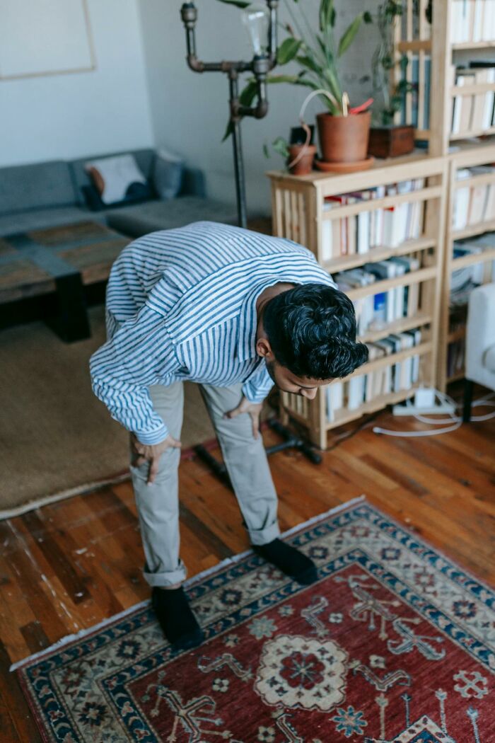 Man in striped shirt bending forward in a cozy living room, illustrating signs of talking to a psychopath experience.