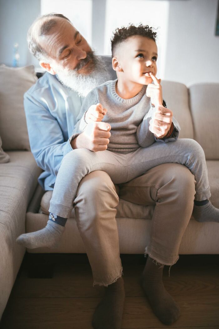 Elderly man and child sitting on couch, child appearing thoughtful, related to creepy and terrifying imaginary friends experiences.