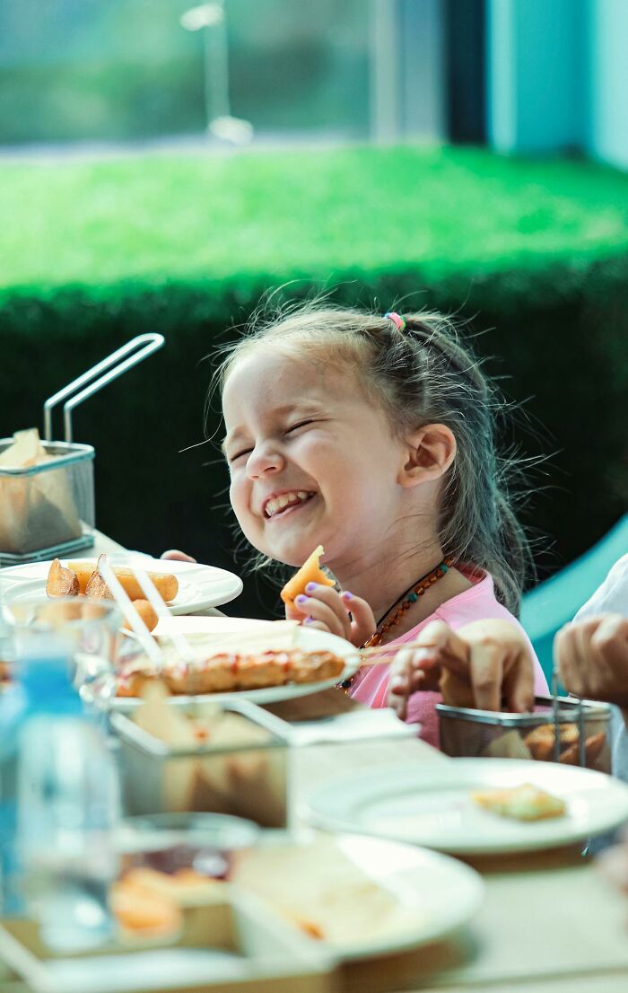 Smiling child enjoying food at a table, capturing a heartwarming moment with harmless secrets and joy.
