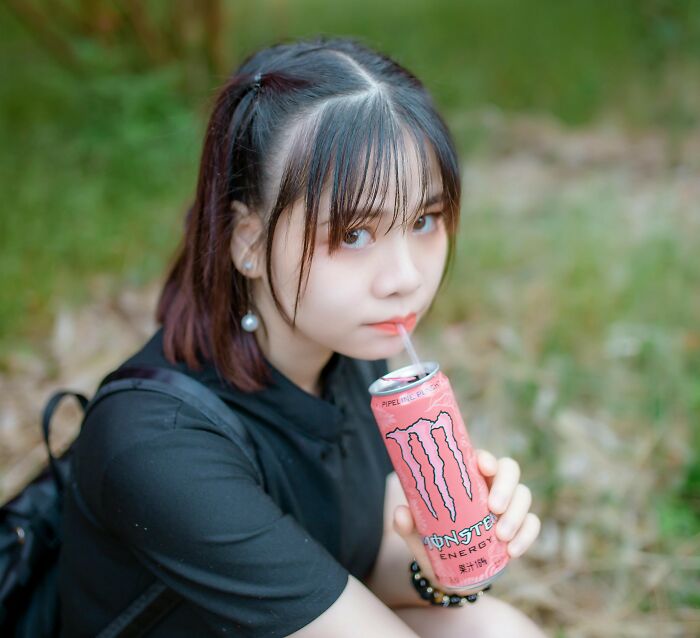Young woman sitting outdoors drinking from a can, representing shopping as a non-substance dependency challenge.