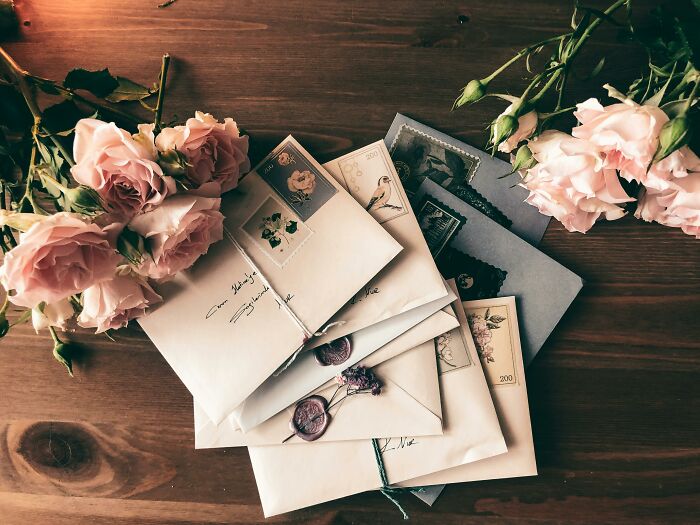 Stack of vintage letters with pink roses on wooden table, symbolizing secrets discovered after someone passed away