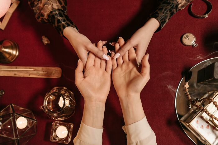 Two people holding hands on a table with candles and mystical items, evoking smooth pickup lines moments.