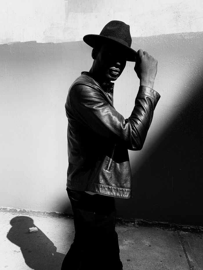 Silhouetted night shift worker in leather jacket and hat standing against a wall, evoking chilling paranormal encounters.