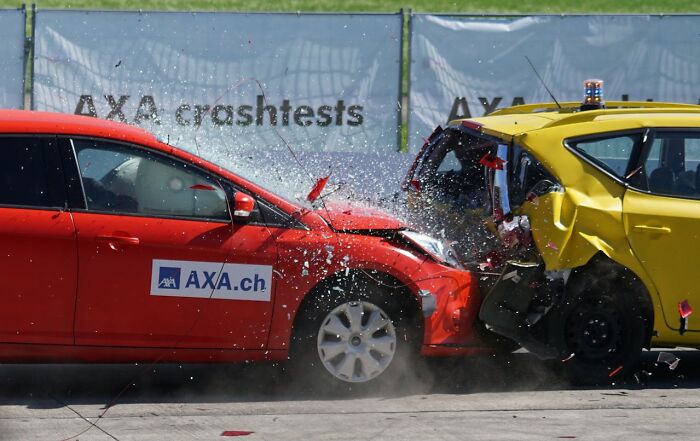 Red car crash testing impact with yellow vehicle demonstrating car safety, related to psychics predicted events experience.