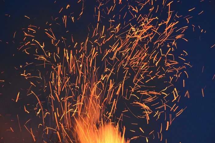 Sparks flying from fire at night, illustrating tiny human mistakes that changed the course of history forever.
