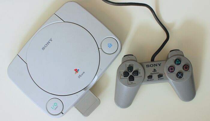 Sony PlayStation console and controller on a white surface, representing tiny human mistakes that changed history.