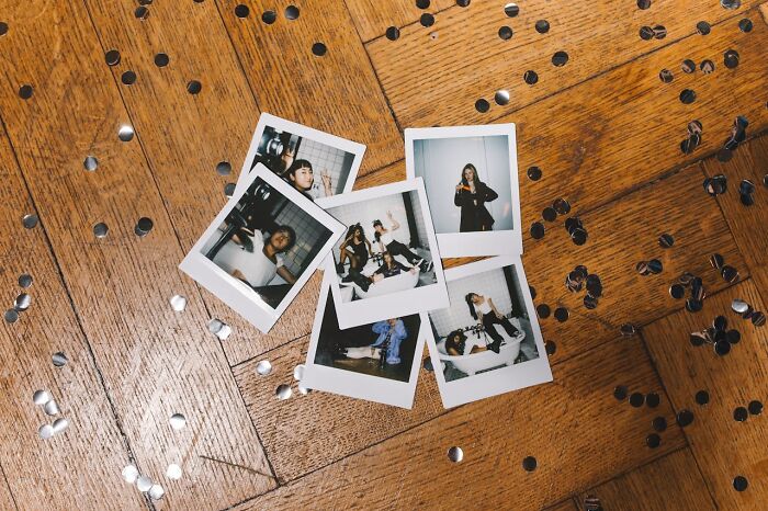Polaroid photos of teens scattered on a wooden floor with confetti, hinting at snooping parents uncovering teen secrets. - 52