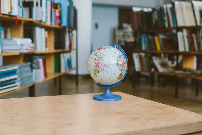 Globe on a table in a library setting, representing a general knowledge geography test with alphabet clues.