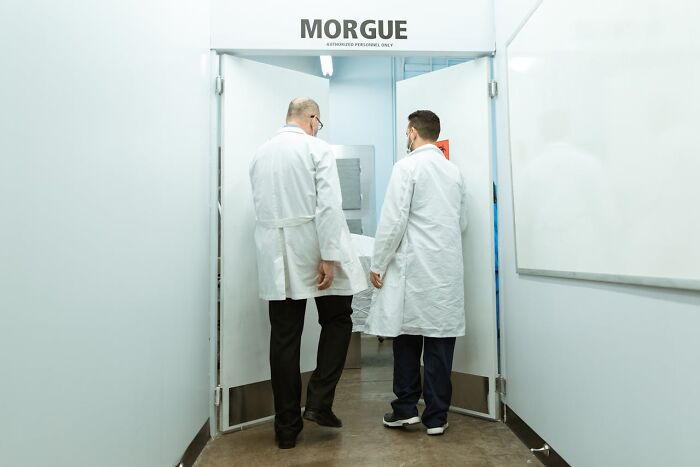 Two night shift workers in lab coats entering a morgue, evoking chilling paranormal encounters at night.