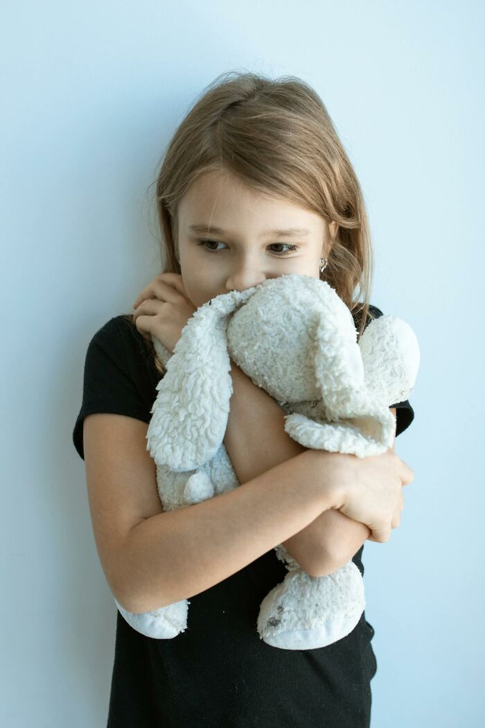 Young girl hugging a soft stuffed bunny tightly, capturing a heartwarming moment of innocence and secret comfort.