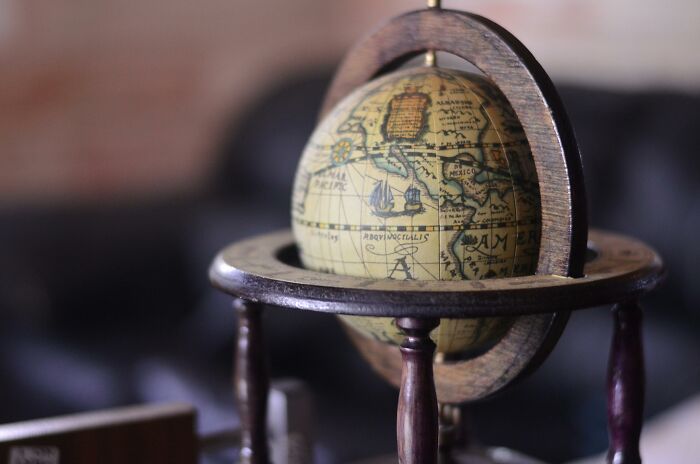 Vintage globe on wooden stand with antique map details, representing history and the challenge of spotting truth from myth.