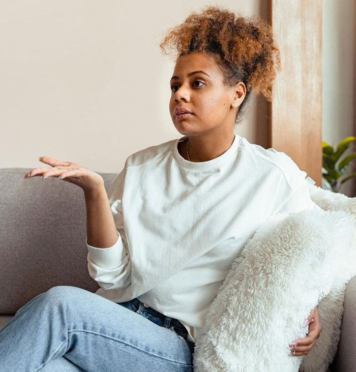 Young woman sitting on a couch looking frustrated after hosting old friend with unexpected wild requests at home Young woman sitting on a couch looking frustrated after hosting old friend with unexpected wild requests at home