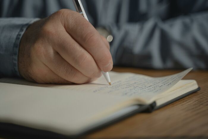 Person writing in a notebook revealing hidden families and mob money secrets discovered after someone passed away.