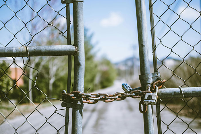 Chain and padlock securing a metal gate blocking the road, symbolizing restriction or threat involving young woman and cops.