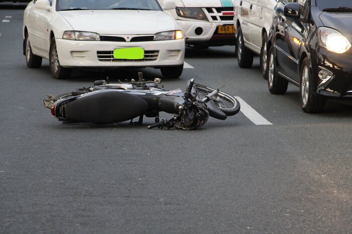 Motorcycle lying on busy road after an accident, illustrating real people surviving crazy situations on the street.