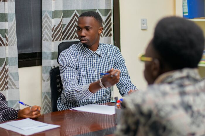 Young man in a job interview pointing in discussion, highlighting interview red flags and signs of a toxic workplace environment.