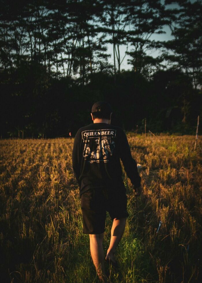 Man walking alone in dark field at dusk, evoking night shift workers paranormal encounters and eerie atmosphere