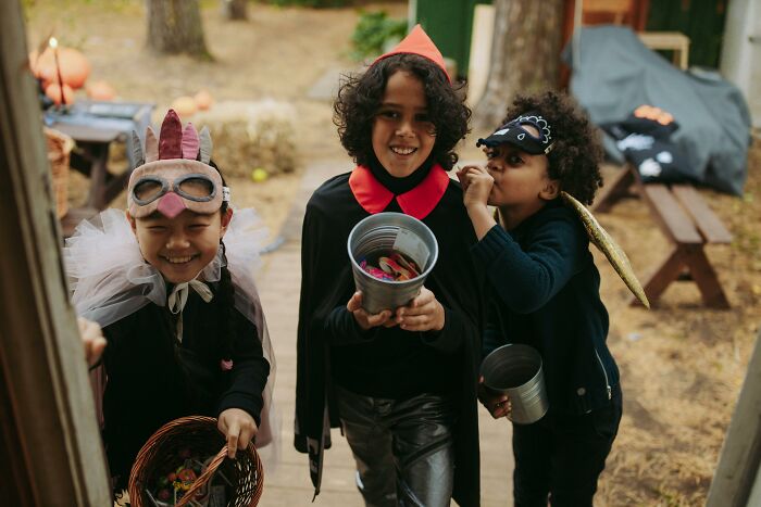 Three kids in Halloween costumes holding buckets of candy, showcasing totally safe things that people can’t stop freaking out about.