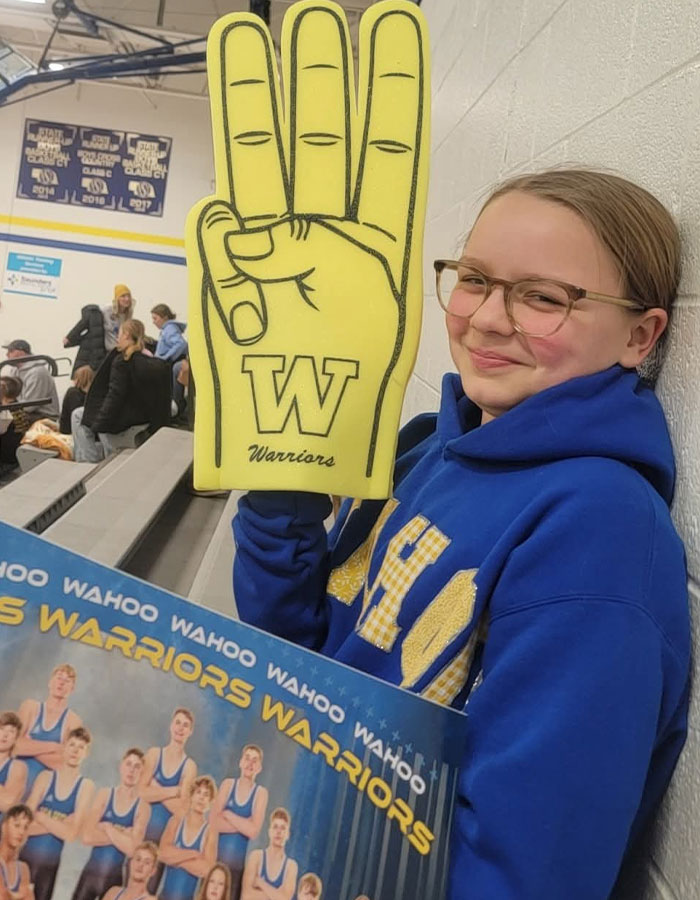 Young fan holding foam finger and team poster at indoor game, showing support for Warriors and highlighting heartbreaking final phone call.