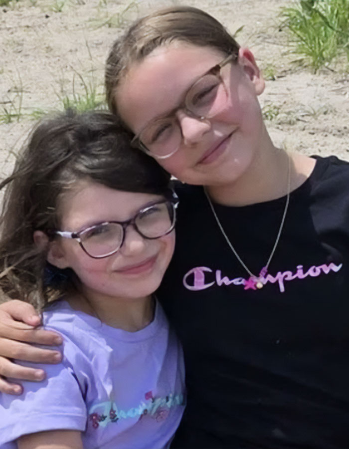 Two young girls wearing glasses smiling and hugging, representing daughters from heartbreaking final phone call before explosion.