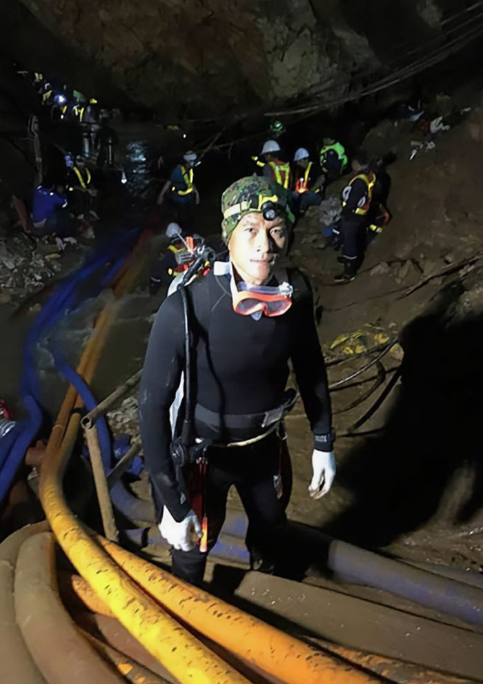 Rescue diver in a cave surrounded by rescue team and equipment in a dramatic pre-disaster photo taken before disaster.