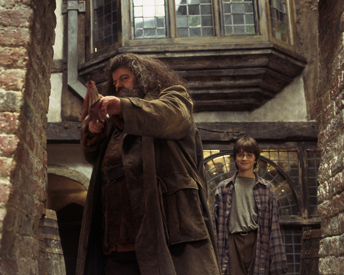 Actors on the Harry Potter series set, one aiming a wooden wand, surrounded by rustic brick walls and old windows. Actors on the Harry Potter series set, one aiming a wooden wand, surrounded by rustic brick walls and old windows.