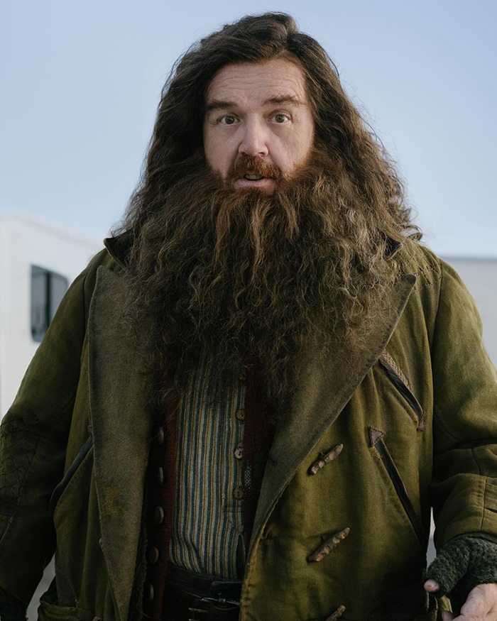 Actor dressed as Hagrid in Harry Potter series costume with long hair and beard on set outdoors. Actor dressed as Hagrid in Harry Potter series costume with long hair and beard on set outdoors.