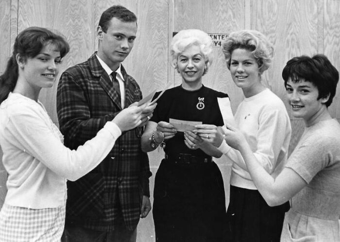 LA women and a man smiling and holding cards together in a black and white 1960s vintage photo.