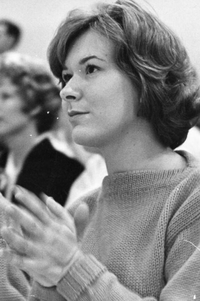 Young LA woman in 1962 wearing a sweater, attentively clapping in a black and white photo capturing life moments.