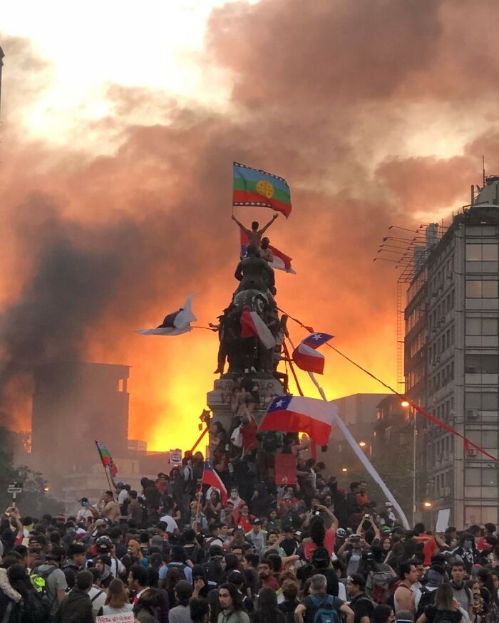 Crowd of common folk protesting at sunset with flags and smoke, making a huge mark in society and history.